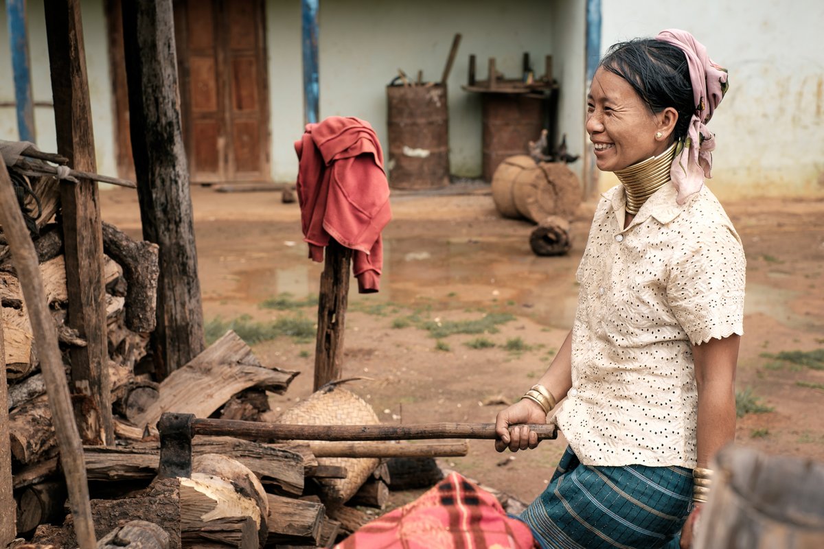 Pan Pet, Myanmar - May 25, 2016: Rural life of Padaung (Karen) hill tribe village in Myanmar. Positive senior long neck woman in brass rings around their neck doing home work